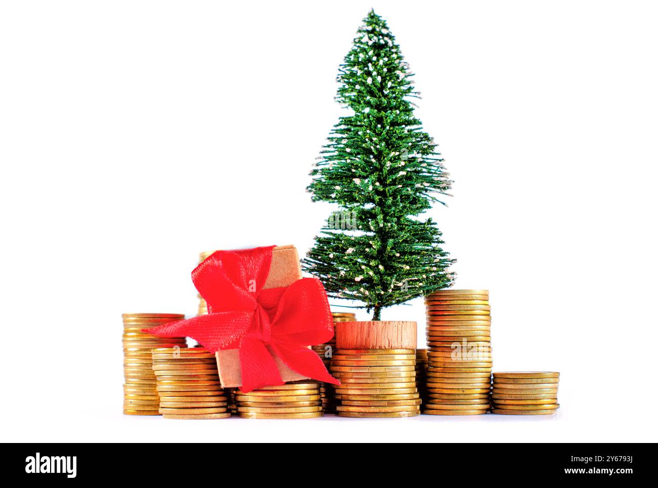 Mini-Weihnachtsbaum und Geschenkbox auf goldenen Münzen, symbolisiert Reichtum, Weihnachtsstimmung und festliche Feierlichkeiten. Stockfoto