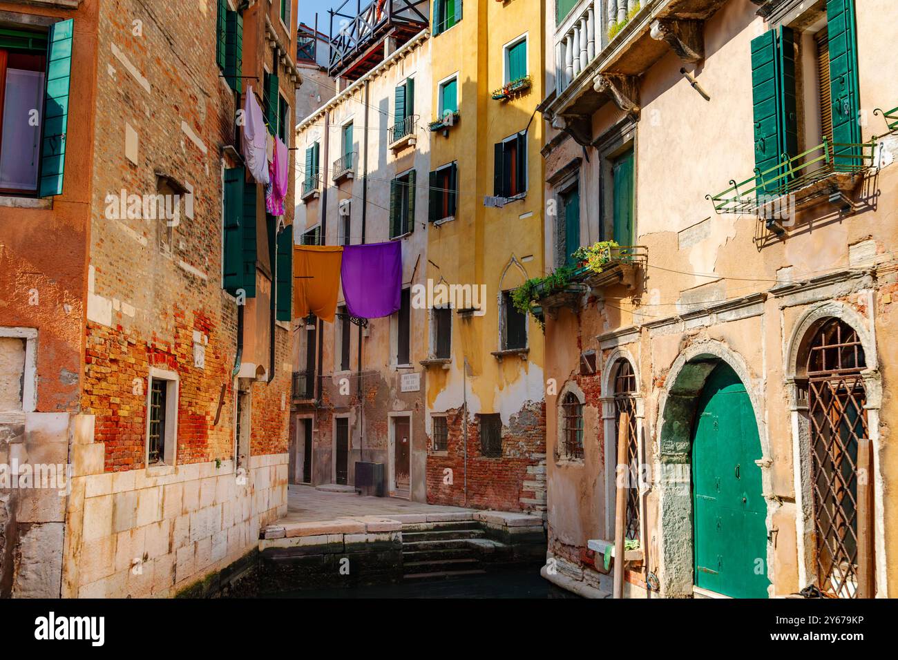 Waschen hängt zum Trocknen auf einer Linie zwischen zwei Gebäuden entlang des Rio Terà de le Carampane, einer Seitenstraße in der Sestiere von San Polo, Venedig, Italien Stockfoto