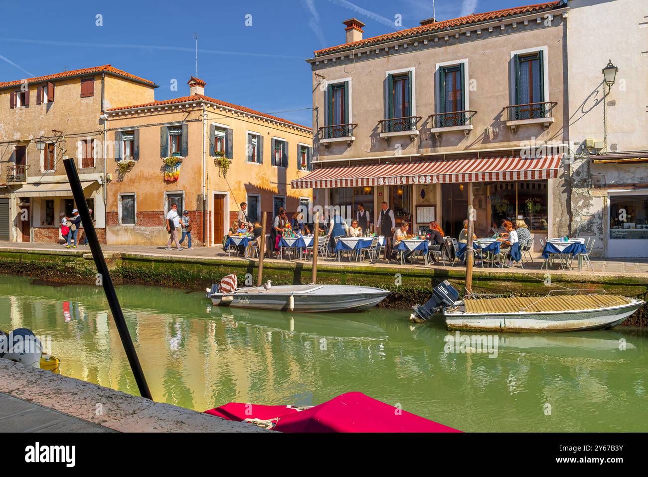 Leute, die vor dem Ristorante Dalla Mora sitzen, am Rio dei vetrai, einem Kanal auf der Insel Murano in der Nähe von Venedig, Italien, Stockfoto