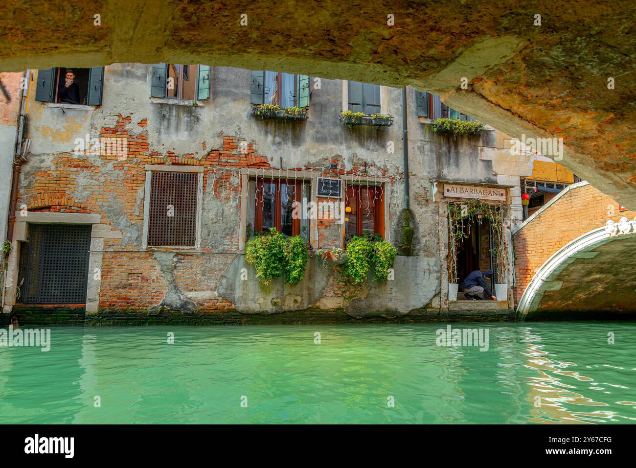 Ein Mann putzt die Stufen am Kanaleingang zum Al Barbacani Restaurant am rio del Mondo Novo Kanal im Castello Sestiere von Venedig, Italien Stockfoto