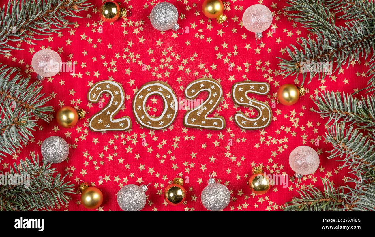Neujahrsdatum 2025 arrangiert aus Weihnachtskuchenkeksen auf rotem Tischtuch, verziert mit Ornamenten und Kranz Stockfoto