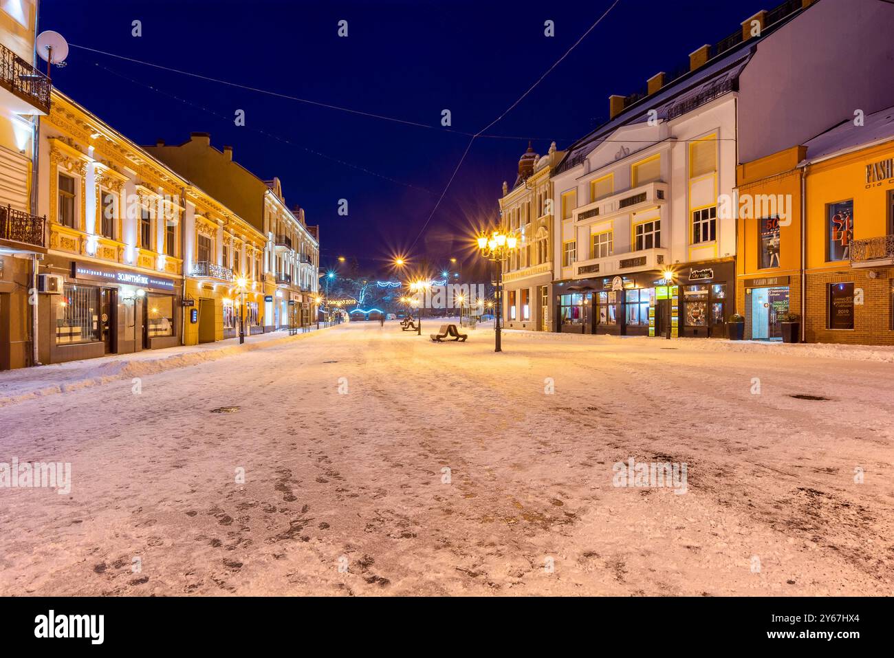 uschhorod, ukraine - 6. januar 2019: Nächtliche Winterstadt. weihnachtsbeleuchtung. Die Straße ist mit Schnee bedeckt. Szene in der Nähe des petofi-Platzes Stockfoto