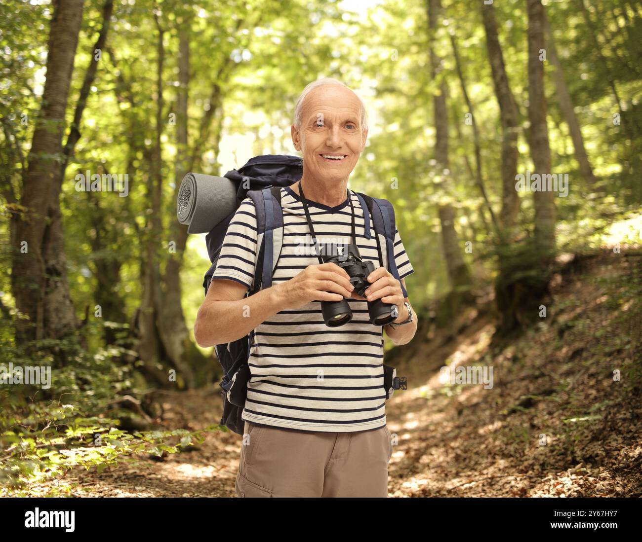 Reifer männlicher Wanderer, der ein Fernglas in einem Wald hält Stockfoto