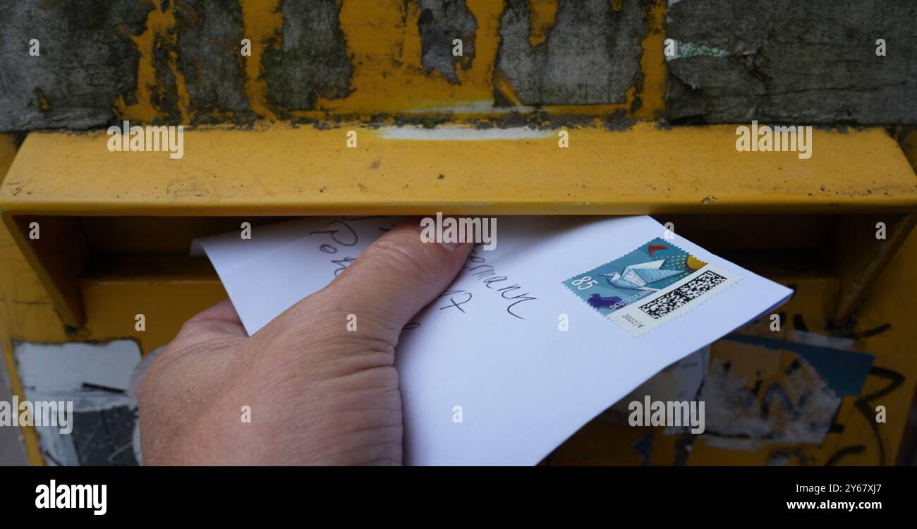 Hamburg, Deutschland. September 2024. ABBILDUNG – Ein Passant legt einen Brief mit einem 85-Cent-Stempel in einen Briefkasten der Postfiliale. Die Bundesnetzagentur entscheidet ab Januar 2025 über das Briefportogeschäft. Die Bundesnetzagentur trifft jetzt eine "Benchmark-Entscheidung" - sie setzt einen prozentualen Korridor fest, innerhalb dessen die Kosten für den Versand aller Briefe steigen können. Die Schweizerische Post wird dann genau festlegen, wie viel teurer die einzelnen Postarten werden sollen, was wiederum noch von der Bundesnetzagentur genehmigt werden muss. Quelle: Marcus Brandt/dpa/Alamy Live News Stockfoto