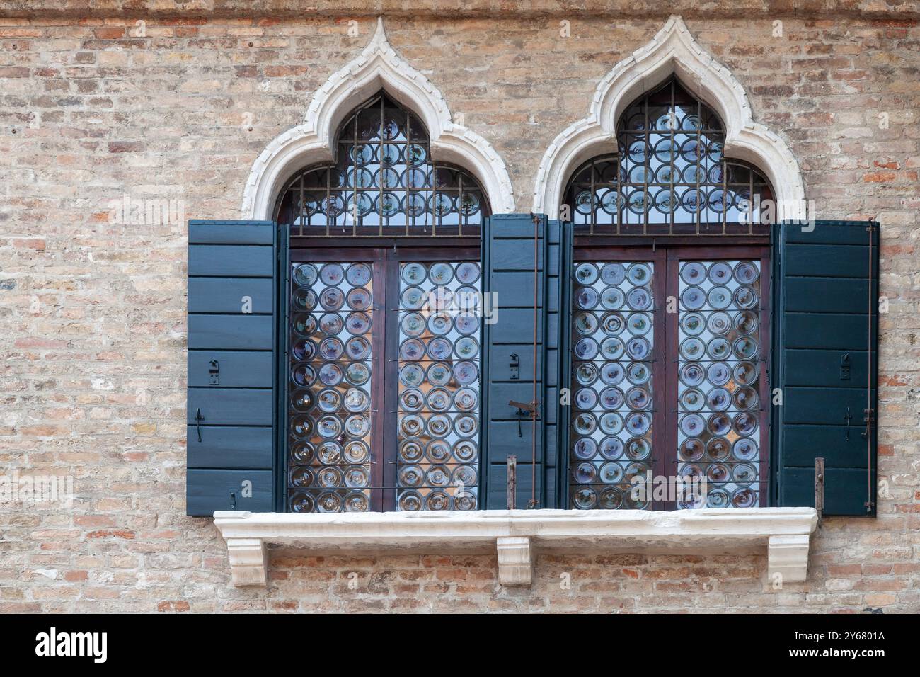 Gotisches Flaschenglas oder Kronglas mit grünen Fensterläden, Venedig, Italien aus mundgeblasenen mittelalterlichen Rundstücken aus farbigem Glas Stockfoto