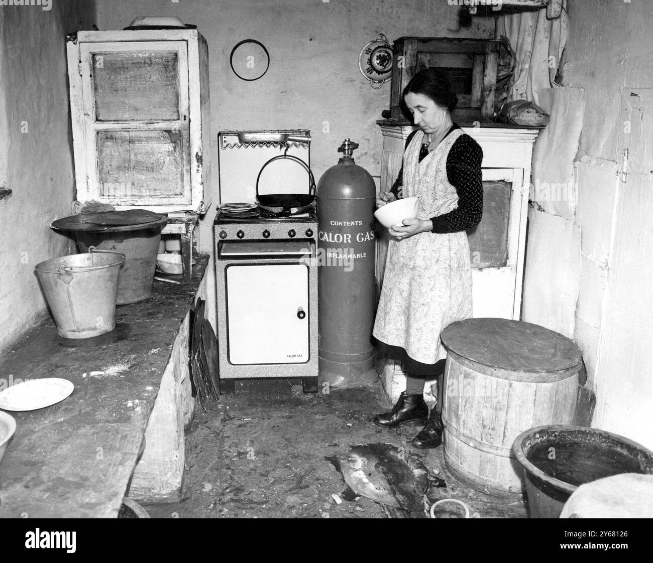 Mrs. Peters ging 1916 mit ihrem Mann auf die Farm. Jetzt eine Witwe, sie ist 59, sieht aber viel jonger aus. Mit Hilfe ihrer beiden Brüder schafft sie es sehr geschickt. Das ist ihre Küche - der einzige moderne Komfort ist das Flaschengas und der Herd - der ungefähr 13 Meilen gebracht wird, wenn eine neue Flasche benötigt wird. - 17. Dezember 1950 Stockfoto