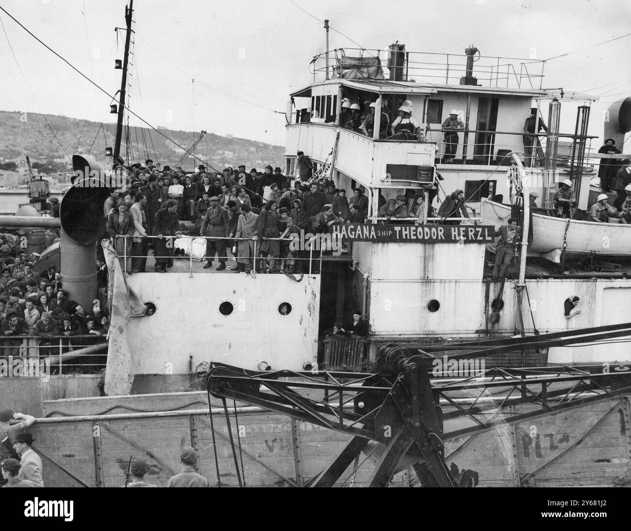 2.700 jüdische Einwanderer landeten in Haifa – Leichen von zwei Toten wurden in der antibritischen Demonstration hochgehalten. 19. April 1947 Fotos, die im Hafen Haifa aufgenommen wurden, als 2.700 illegale jüdische Einwanderer vom Dampfer Guardian unter der jüdischen Flagge ausstiegen. Eines der größten illegalen Schiffe, das Schiff war vom Stamm bis zum Heck überfüllt. An Deck lagen die Leichen der beiden Männer, die bei einem Zusammenstoß getötet worden waren, in jüdische blaue und weiße Fahnen gehüllt. Die Immigranten hielten diese Leichen in Armlänge hoch und riefen den Soldaten auf dem Steg zu: "Du hast sie getötet. Runter mit Bevins Regierung." Trotzdem ist die Stockfoto