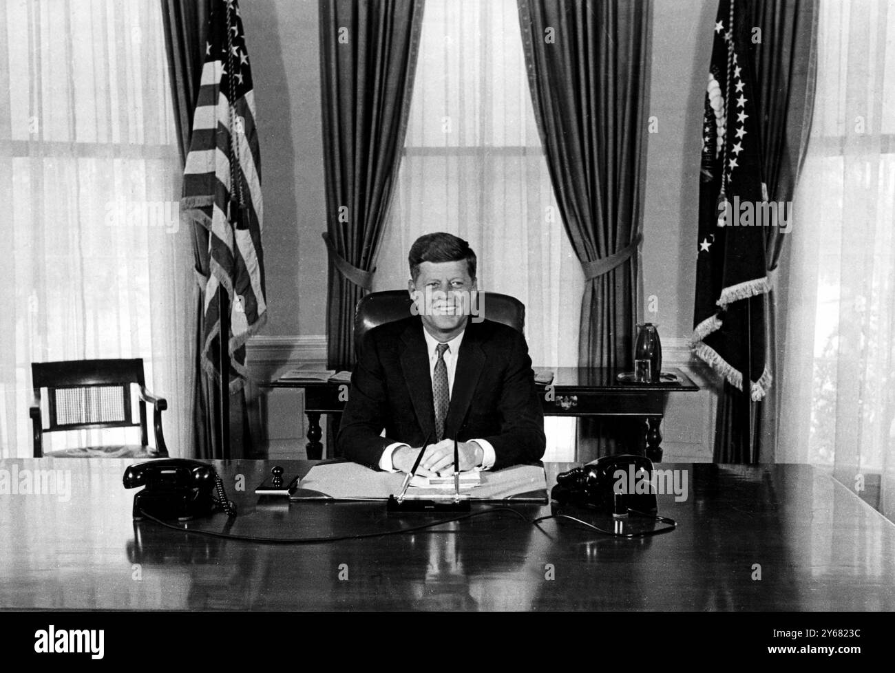 Präsident John Fitzgerald Kennedy sitzt am 21. Januar an seinem Schreibtisch im Weißen Haus und beginnt seinen ersten Arbeitstag als fünfunddreißigster Präsident der Vereinigten Staaten von Amerika. Mit 43 ist Präsident Kennedy der jüngste, der jemals gewählt wurde. In der gestrigen Antrittsrede sagte er den Menschenmassen: "Lasst den Rest der Welt wissen, dass diese Hemisphäre beabsichtigt, Meister in ihrem eigenen Haus zu bleiben." Januar 1961 Stockfoto