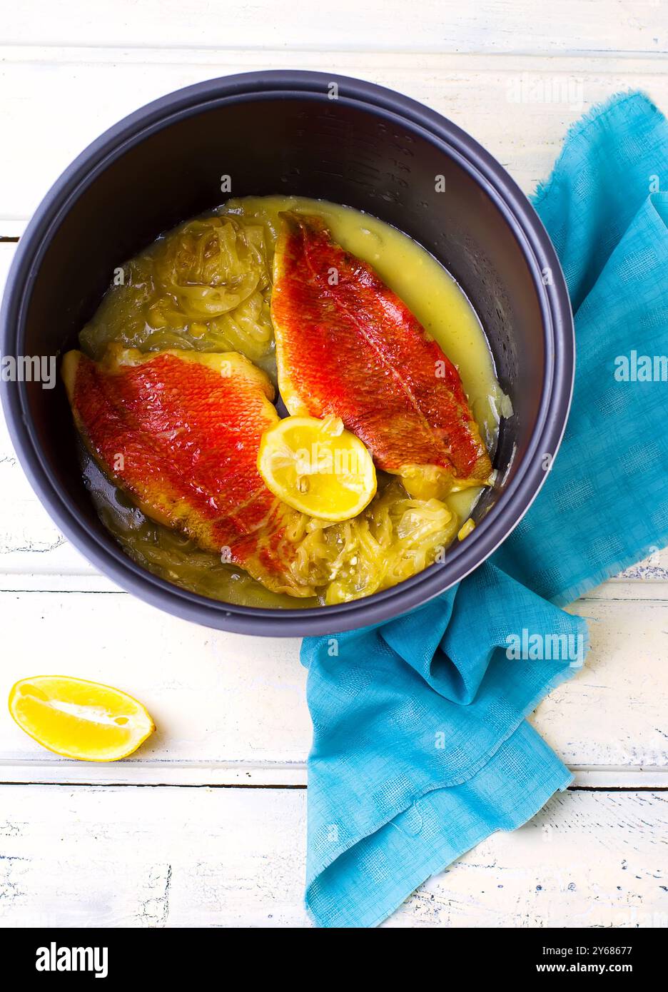 Gedünstetes Filet eines Zerkleinerers mit Zitronensegmenten im Crockpot. Draufsicht. Selektiver Fokus Stockfoto