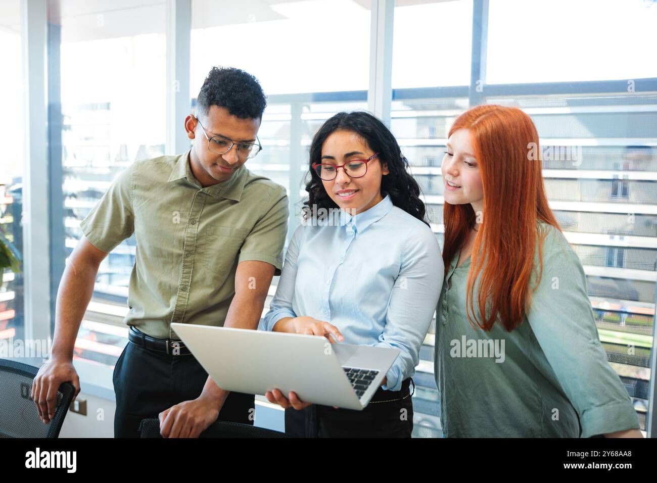 Junge fröhliche Teamarbeit Geschäftsleute, die an einem Projekt mit Laptop in einem gut beleuchteten Konferenzraum zusammenarbeiten Stockfoto