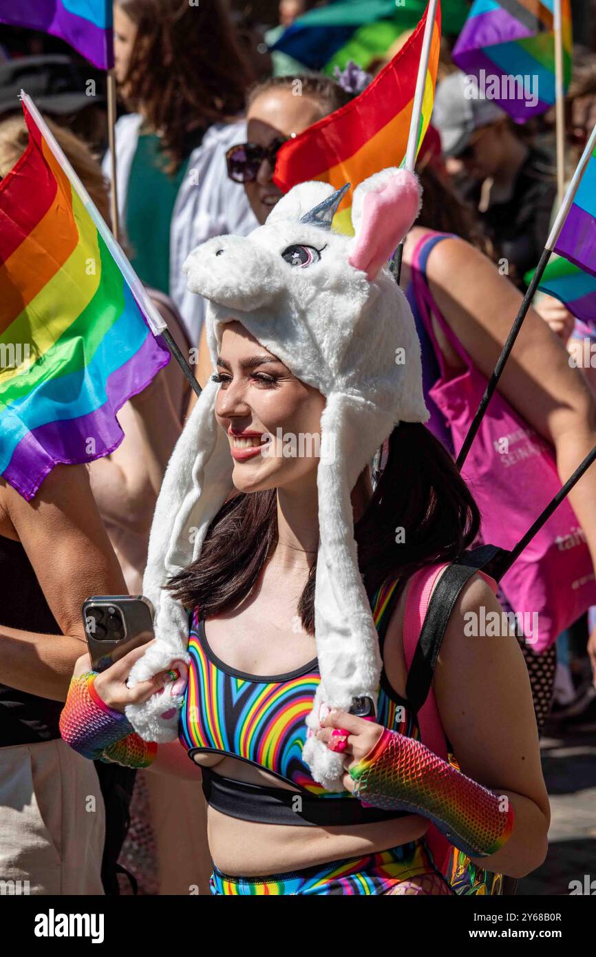 Junge Frau mit RegenbogenBH und lustiger Mütze bei der Helsinki Pride 2024 Parade in Helsinki, Finnland Stockfoto