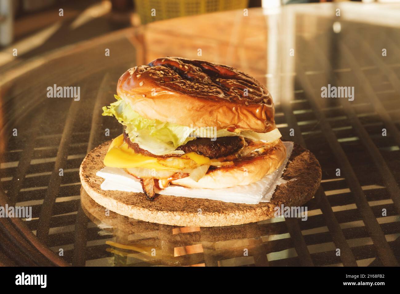 Ein Nahaufnahme eines hausgemachten Burgers mit frischem Salat, geschmolzenem Käse, gegrillten Zwiebeln und einem saftigen Rindfleisch-Patty in einem Sesambrötchen Stockfoto