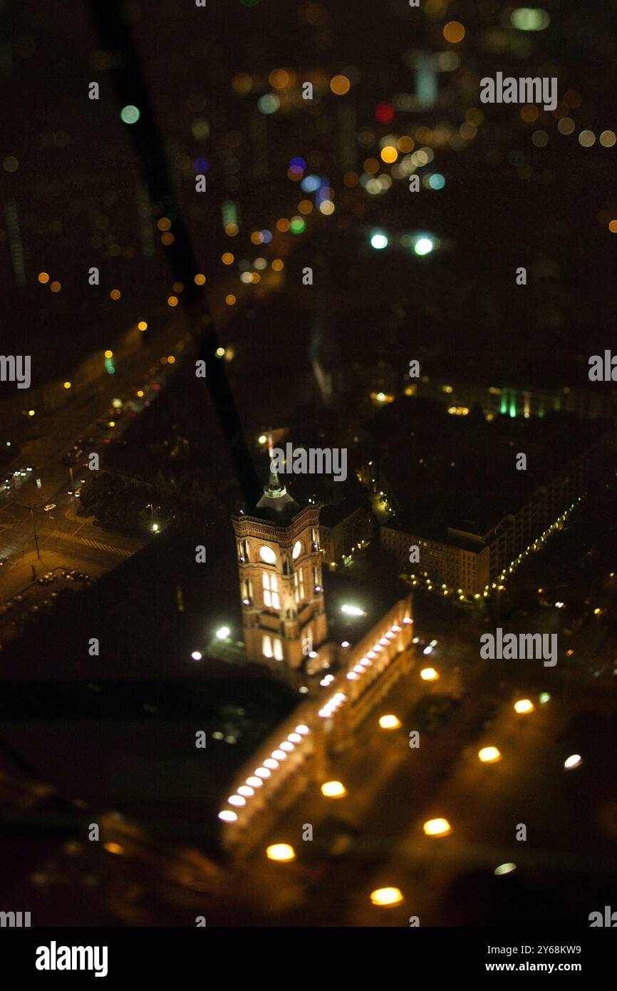 Das Rathaus in Berlin leuchtet nachts warm und wird vom Aussichtspunkt des Fernsehturms aufgenommen, was einen Miniatureffekt erzeugt. Stockfoto