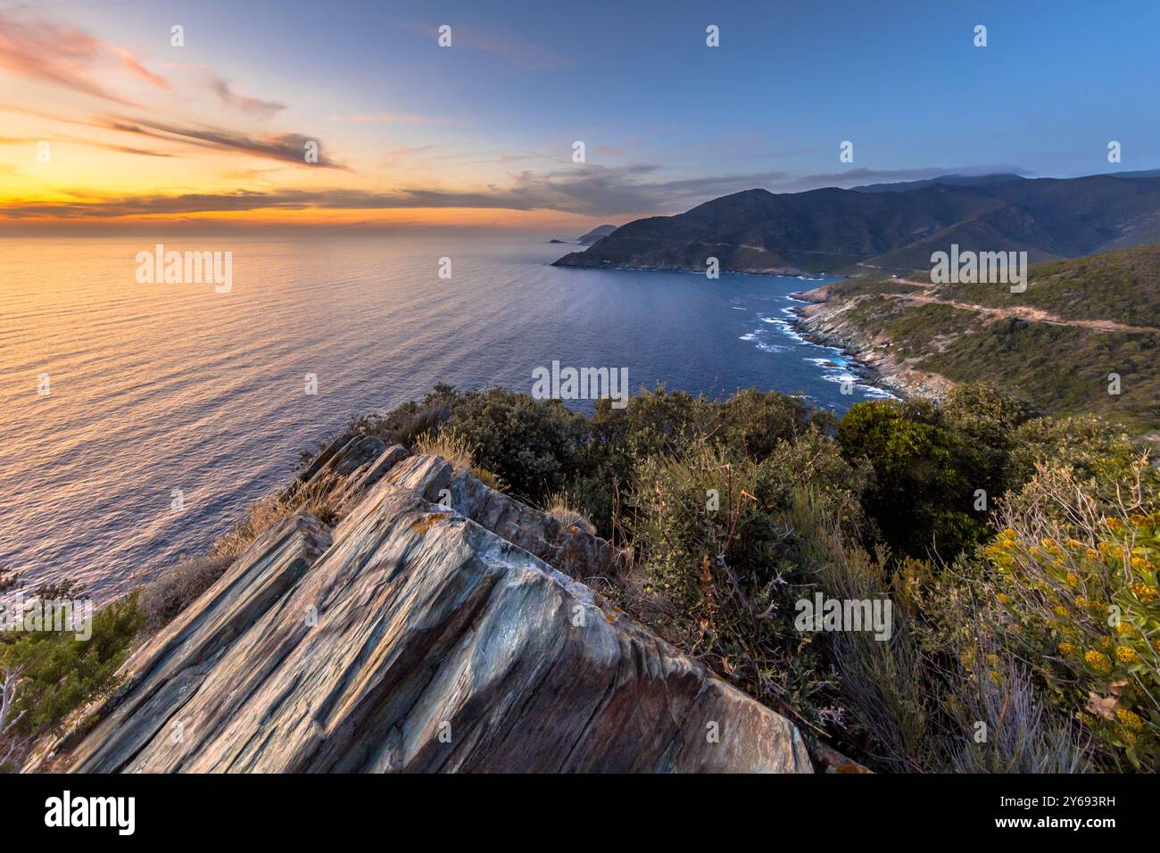 Künstlerische, sedimentäre Felsstrukturen mit Vegetation und Blick auf die Halbinsel Cap Corse auf der Insel Korsika, Frankreich. Stockfoto