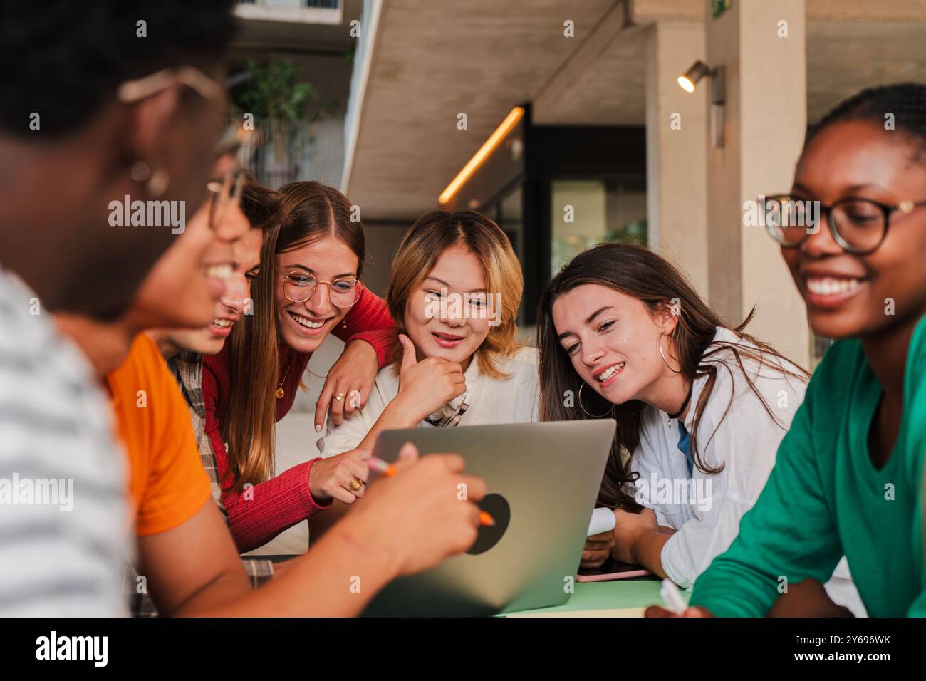 Verschiedene Teenager-Studenten studieren gemeinsam in einer Bibliothek, arbeiten mit einem Laptop an einem Projekt zusammen, fördern Teamarbeit und Kommunikation. Klassenkameraden, die mit einem Computer recherchieren. Hochwertige Fotos Stockfoto