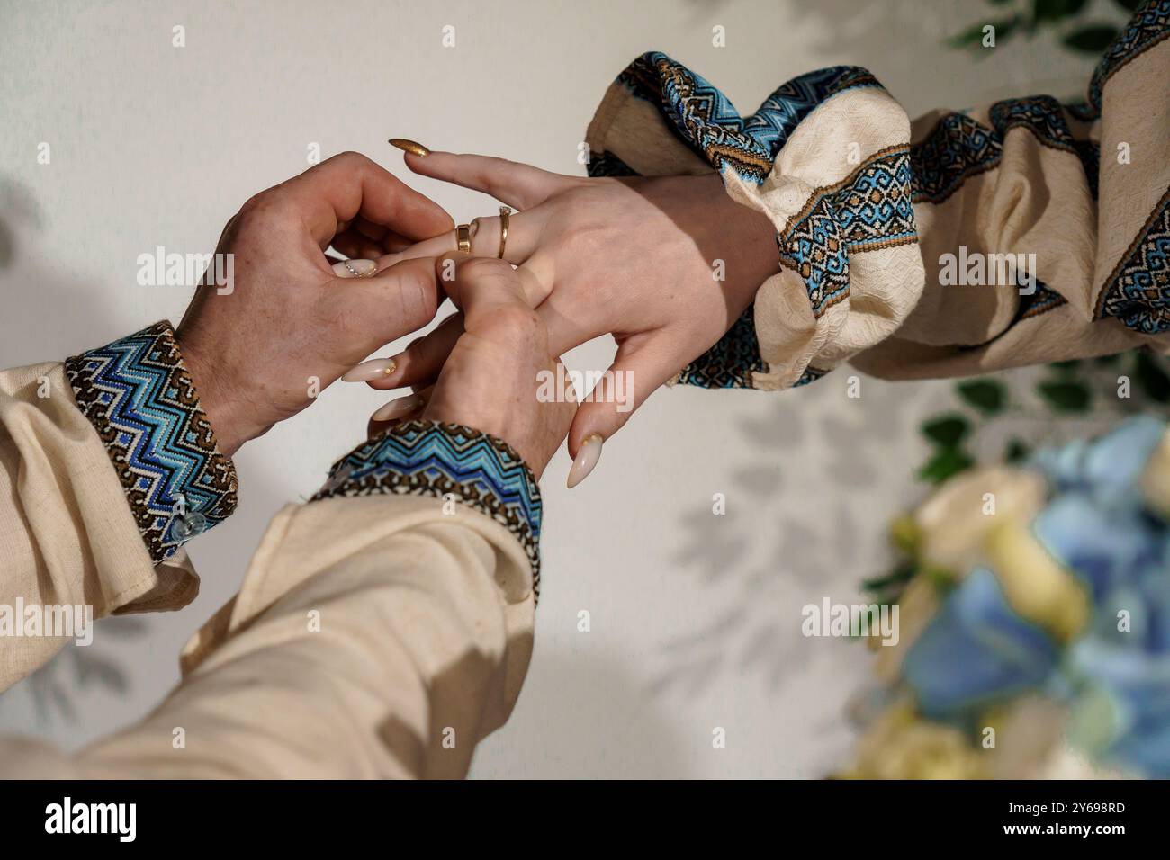 Romantische Verlobungszeremonie mit eleganten Ringen und künstlerischer Kleidung in sanfter Beleuchtung. Stockfoto