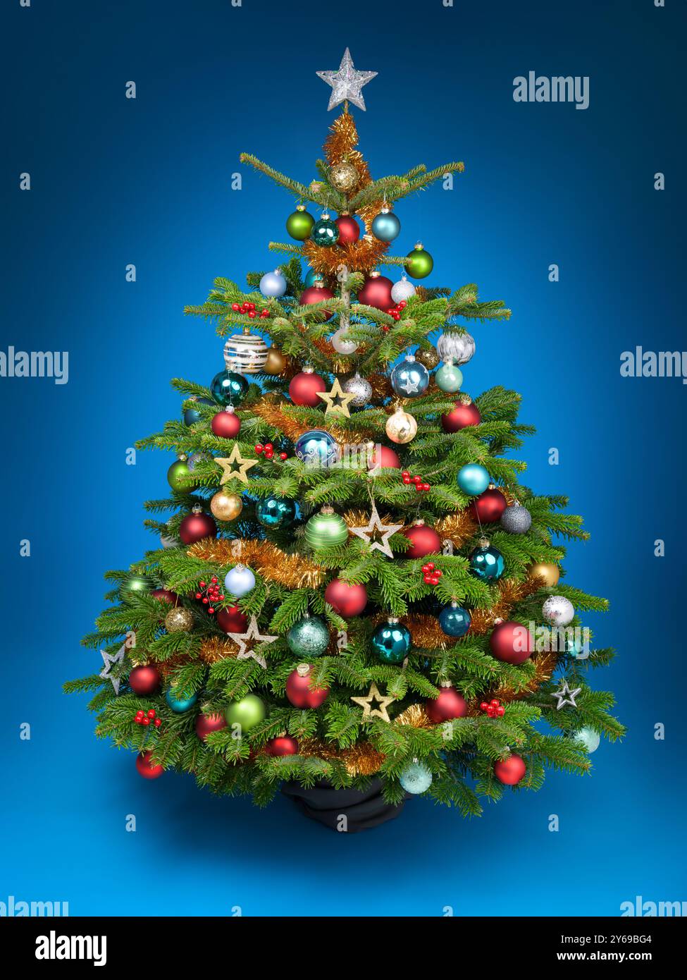 Wunderschön verzierter Weihnachtsbaum mit farbenfrohen Ornamenten auf einem leuchtend blauen Hintergrund Stockfoto