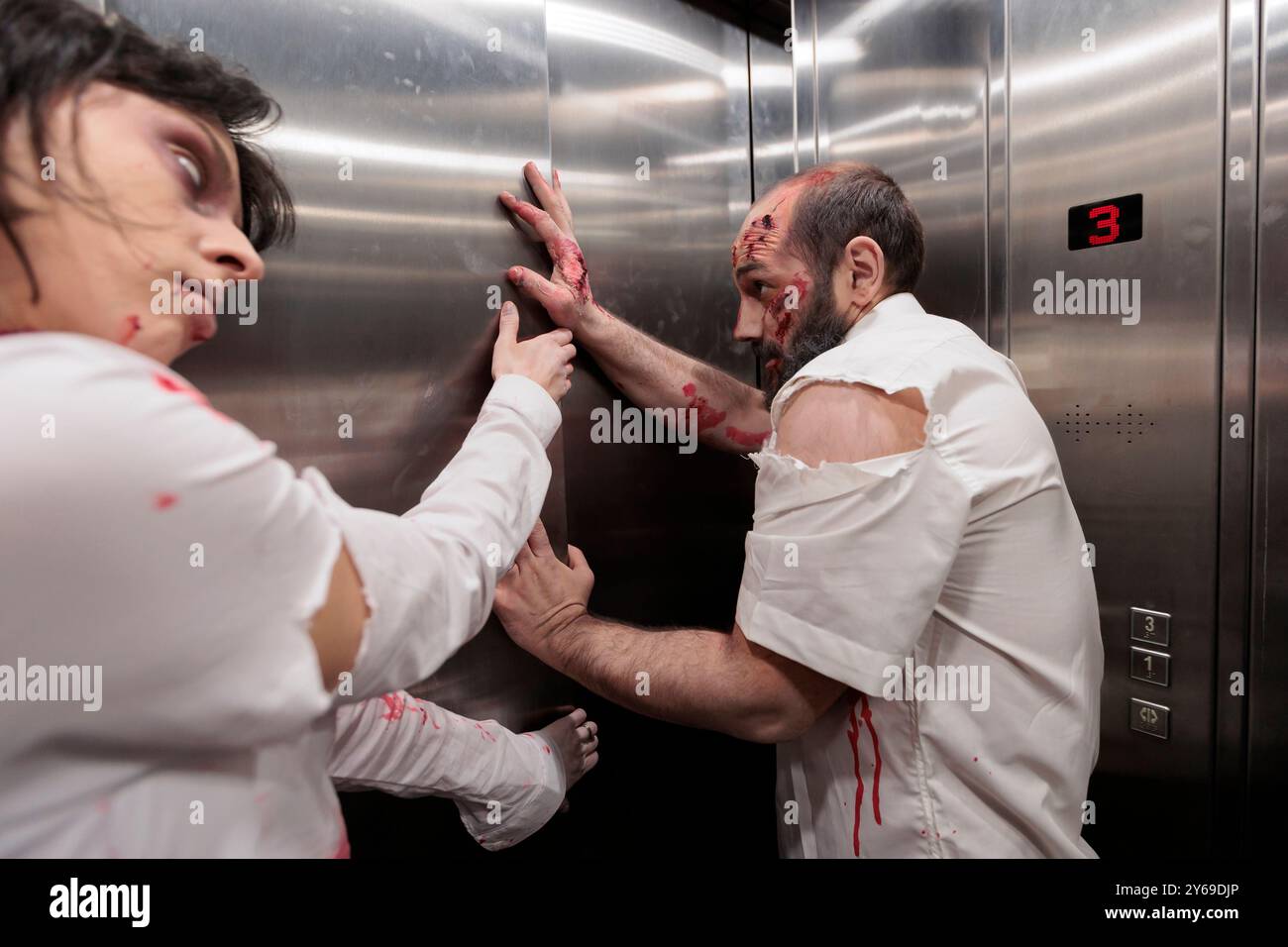 Schauspieler spielen in Horrorfilmen furchterregende besessene Zombies und geben vor, im Aufzug festzusitzen. Mann und Frau in der Rolltreppe, bedeckt mit gefälschten Narben Make-up mit untoten Monstern Rolle in Thriller Film Stockfoto