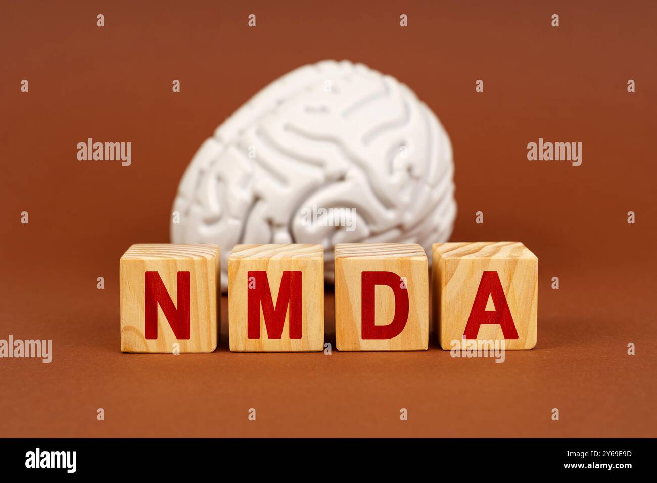 Cubes beschreiben NMDA vor einem stilisierten Gehirn und symbolisieren die Verbindung zwischen dieser Verbindung und neuronalen Prozessen. Stockfoto