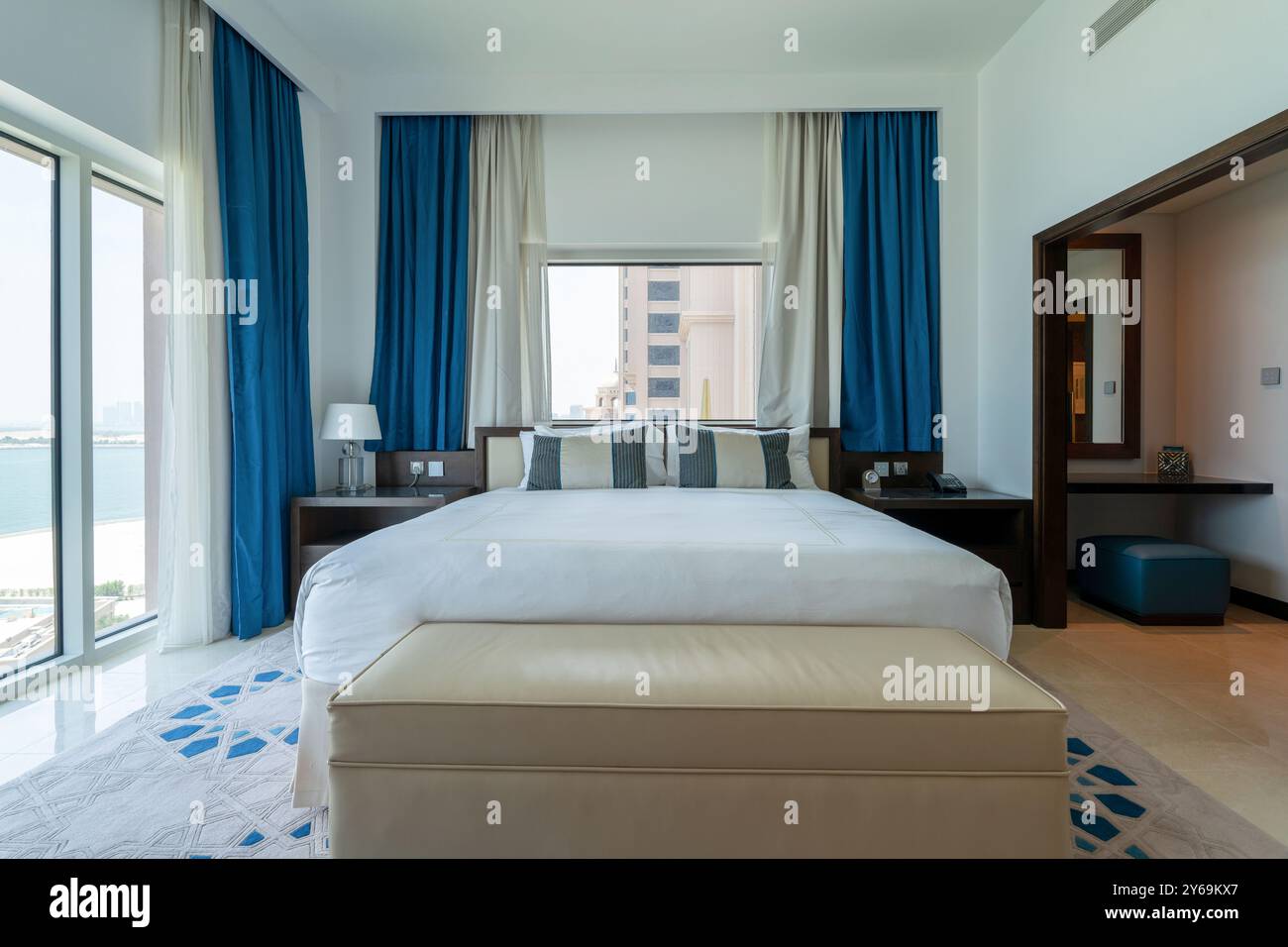 Inneneinrichtung des modernen Schlafzimmers mit weißem Bett und Fenstern mit Meerblick in rixos Marina Abu dhabi Stockfoto
