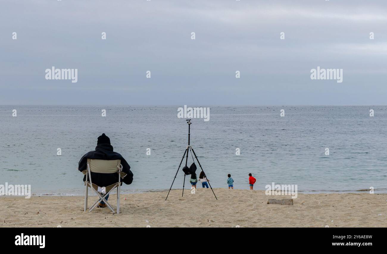 Ein Mann saß in einem Stuhl am Strand und blickte auf das Meer bei Guanaqueros, Coquimbo, Chile Stockfoto