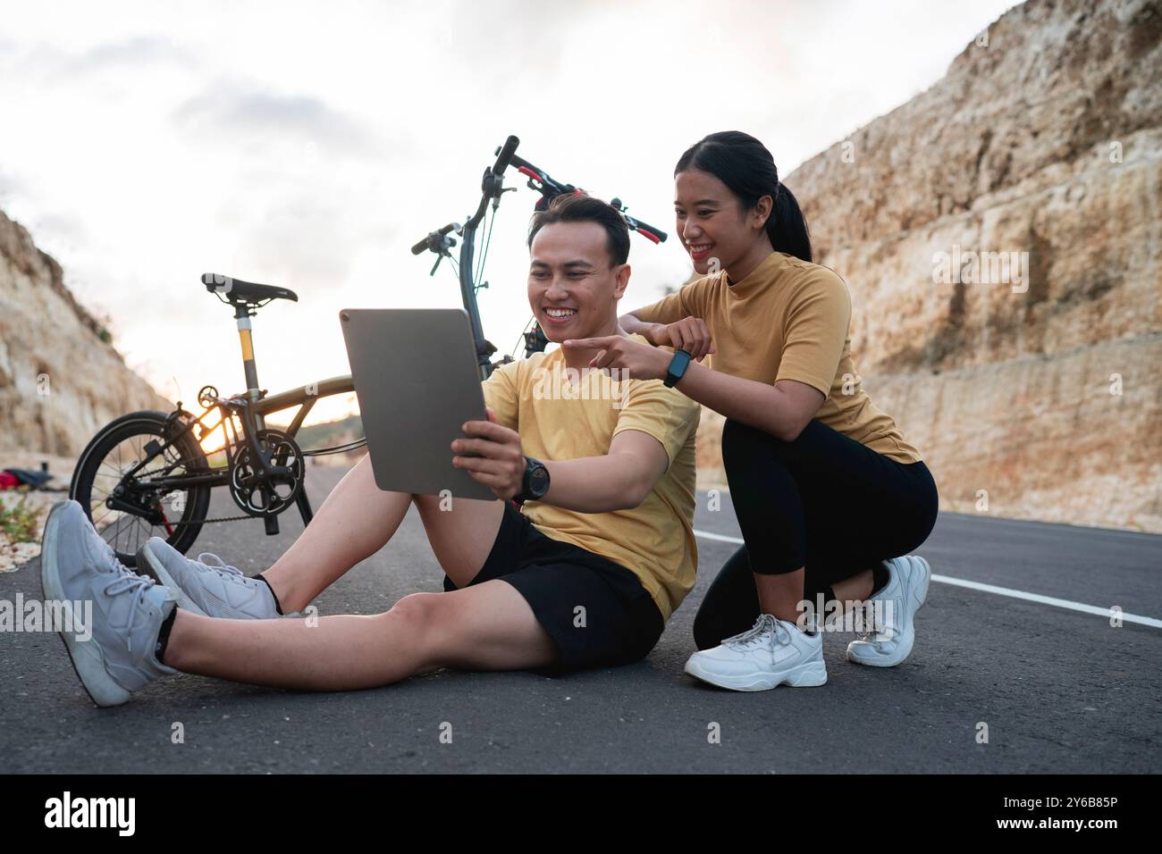 Weibliche und männliche Radfahrerin sitzend und mit einem digitalen Tablet Stockfoto