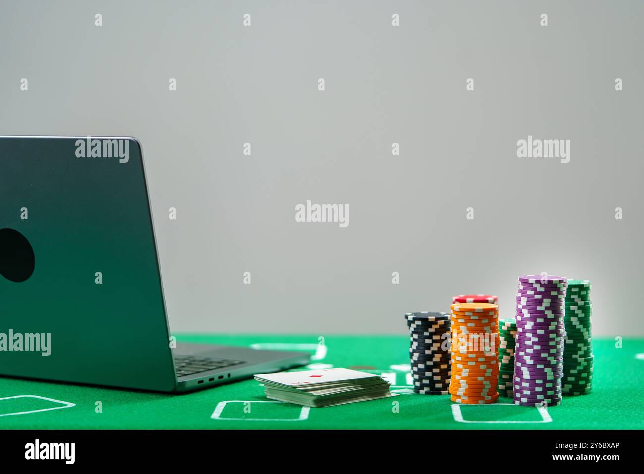 Online-Poker-Spiel-Setup mit bunten Chips und Spielkarten auf einem grünen Tisch Stockfoto