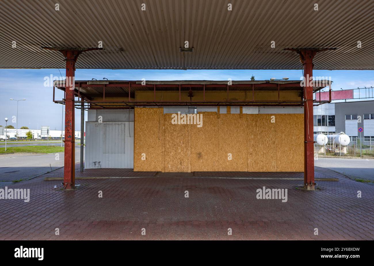 Inaktive und verlassene Tankstelle, inaktive Spender, verschobene Fenster, umzäunter Bereich, alter Bahnhof im Stadtzentrum an der Schnellstraße Stockfoto