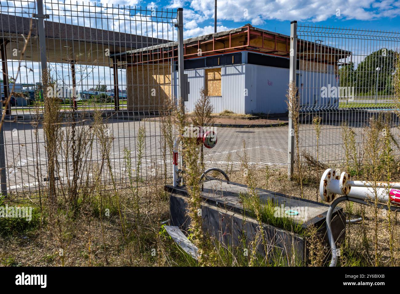 Inaktive und verlassene Tankstelle, inaktive Spender, verschobene Fenster, umzäunter Bereich, alter Bahnhof im Stadtzentrum an der Schnellstraße Stockfoto