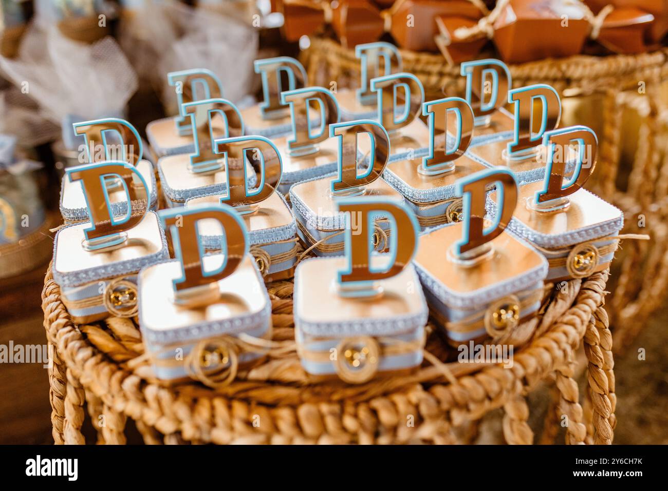 Nahaufnahme von dekorativen Geschenkboxen mit dem Buchstaben D oben, angeordnet auf einem gewebten Korb, ideal für Feiern oder Veranstaltungen. Stockfoto