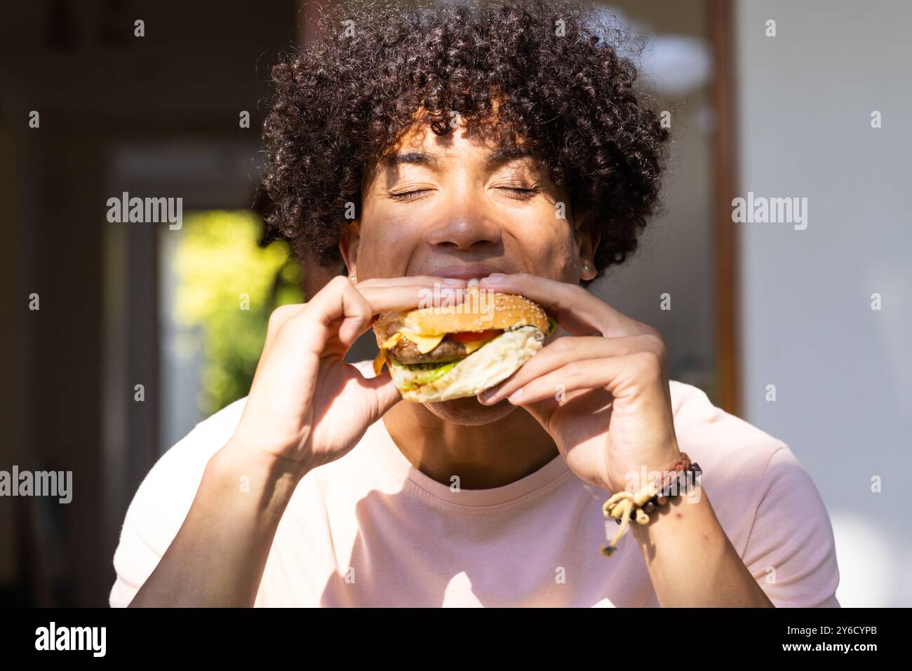 Genießen Sie leckeren Burger, und genießen Sie jeden Happen, während Sie draußen sitzen Stockfoto