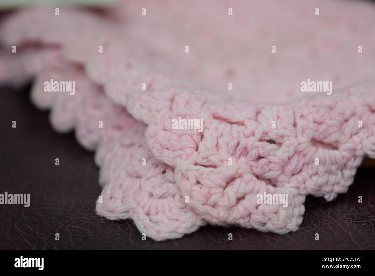 Eine pinkfarbene Babydecke, die vor fast 100 Jahren von Queen Mary bei Hansons Auctioneers in Etwall, Derbyshire, hergestellt wurde, bevor sie am Freitag zur Auktion aufsteigt. Die von Queen Mary gefertigte Häkeldecke trägt noch immer das Etikett „Made by her Majesty the Queen“ im Buckingham Palace. Sie wurde von der Verkäuferin im Haus ihrer 93-jährigen Tante in Wimbledon, Süd-London, entdeckt, aber keiner weiß, woher sie kam. Bilddatum: Mittwoch, 25. September 2024. Stockfoto