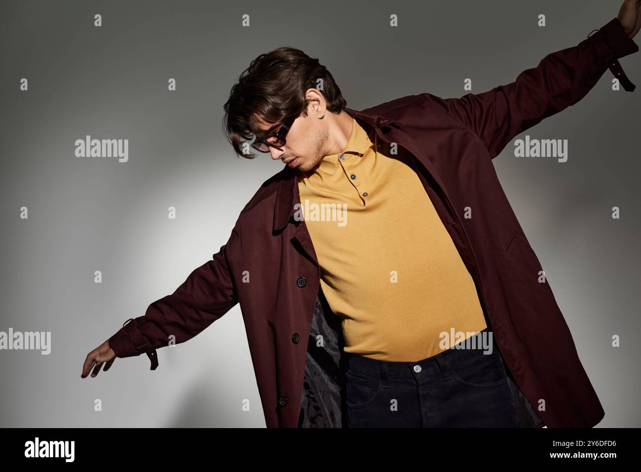 Ein junger Mann in einem stilvollen Herbstoutfit zeigt eine selbstbewusste Pose und unterstreicht so sein Gespür für Mode und Haltung. Stockfoto