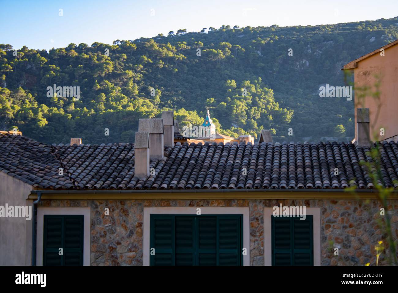 Schwerpunkt eines kleinen Hauses in einem Dorf am Morgen mit seiner Einfachheit, im Hintergrund ein großer Berg voller Laubbäume Stockfoto