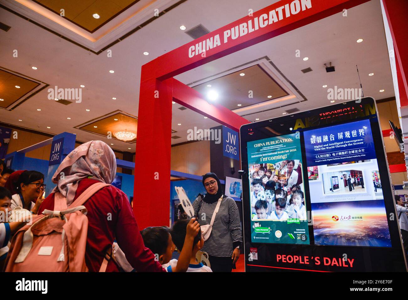 (240925) -- JAKARTA, 25. September 2024 (Xinhua) -- Kinder posieren für Fotos vor der digitalen Pinnwand der People's Daily am Stand der China-Veröffentlichung während der Indonesien International Book Fair 2024 im Jakarta Convention Center in Jakarta, Indonesien, 25. September 2024. Eine Delegation chinesischer Verlage präsentierte am Mittwoch auf der Indonesien International Book Fair (IIBF) 2024, die vom September 25-29 in Jakarta stattfand, mehr als 700 Bände chinesischer Premiumbücher. Organisiert von China National Sci-Tech Information Import & Export Co., Ltd., die Sammlung enthielt über 400 Arten von Büchern, Cove Stockfoto