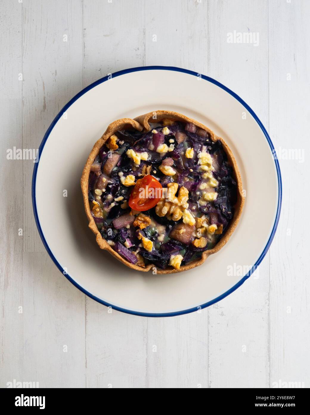 Individuelle vegane Quiche mit Gemüse und Rotkohl. Tisch mit Draufsicht und Dekoration. Stockfoto