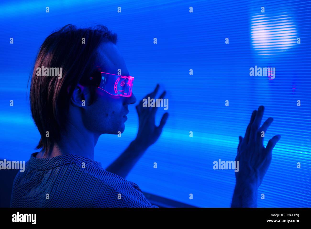 Futuristisches Porträt eines gutaussehenden Mannes mit intelligenter Neonbrille berühren einen Neonwand Hintergrund Metaverse digitale Cyber World Technologie, Mann mit VR Stockfoto
