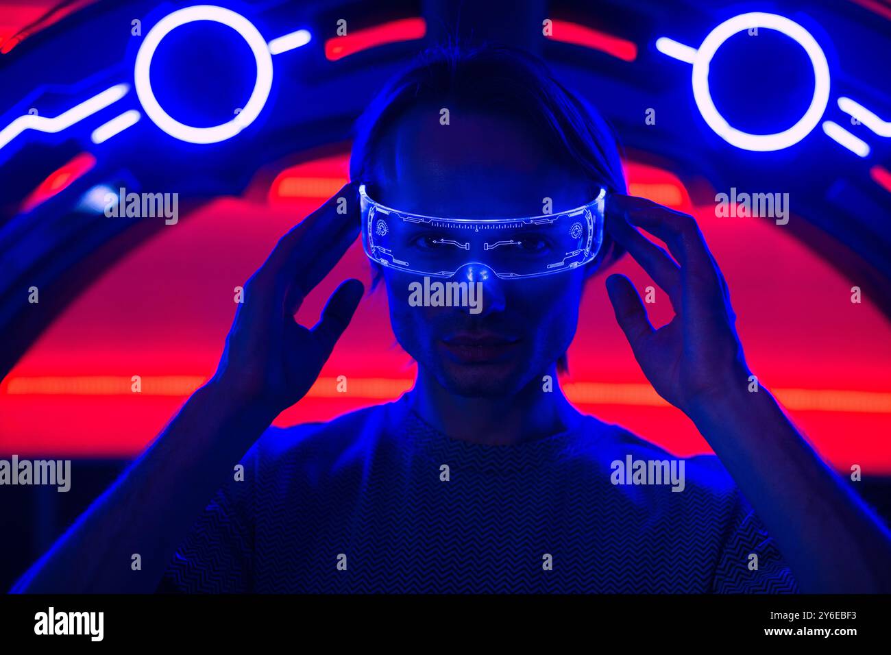 Kreativer futuristischer Mann mit intelligenter Neonbrille in einem Neonraum ein neonblauer Wandhintergrund Metaverse digitale Cyber World Technologie Stockfoto