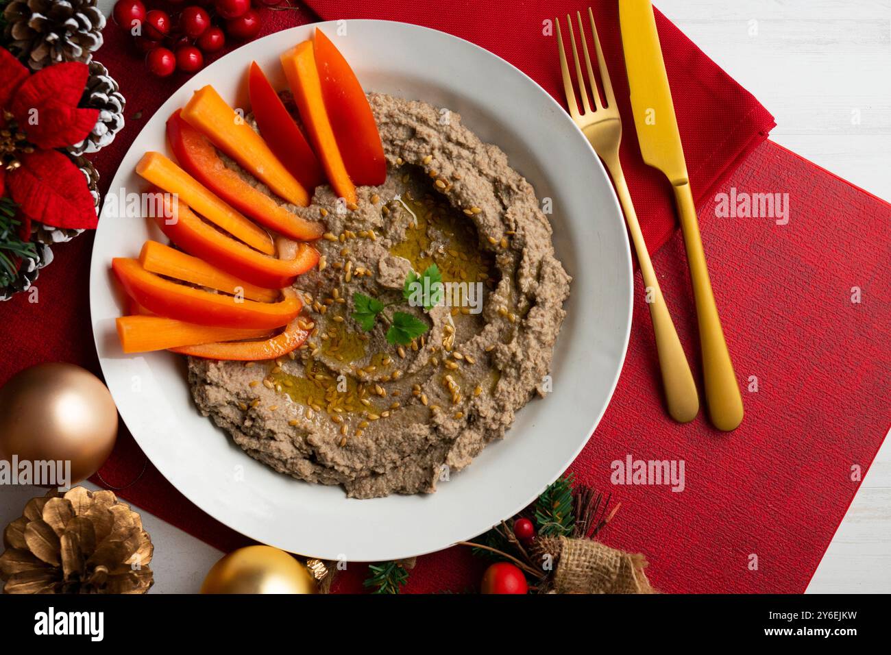 Linsenhummus mit Karotten- und Paprikaroditen. Tisch mit Blick von oben mit Weihnachtsdekoration. Stockfoto