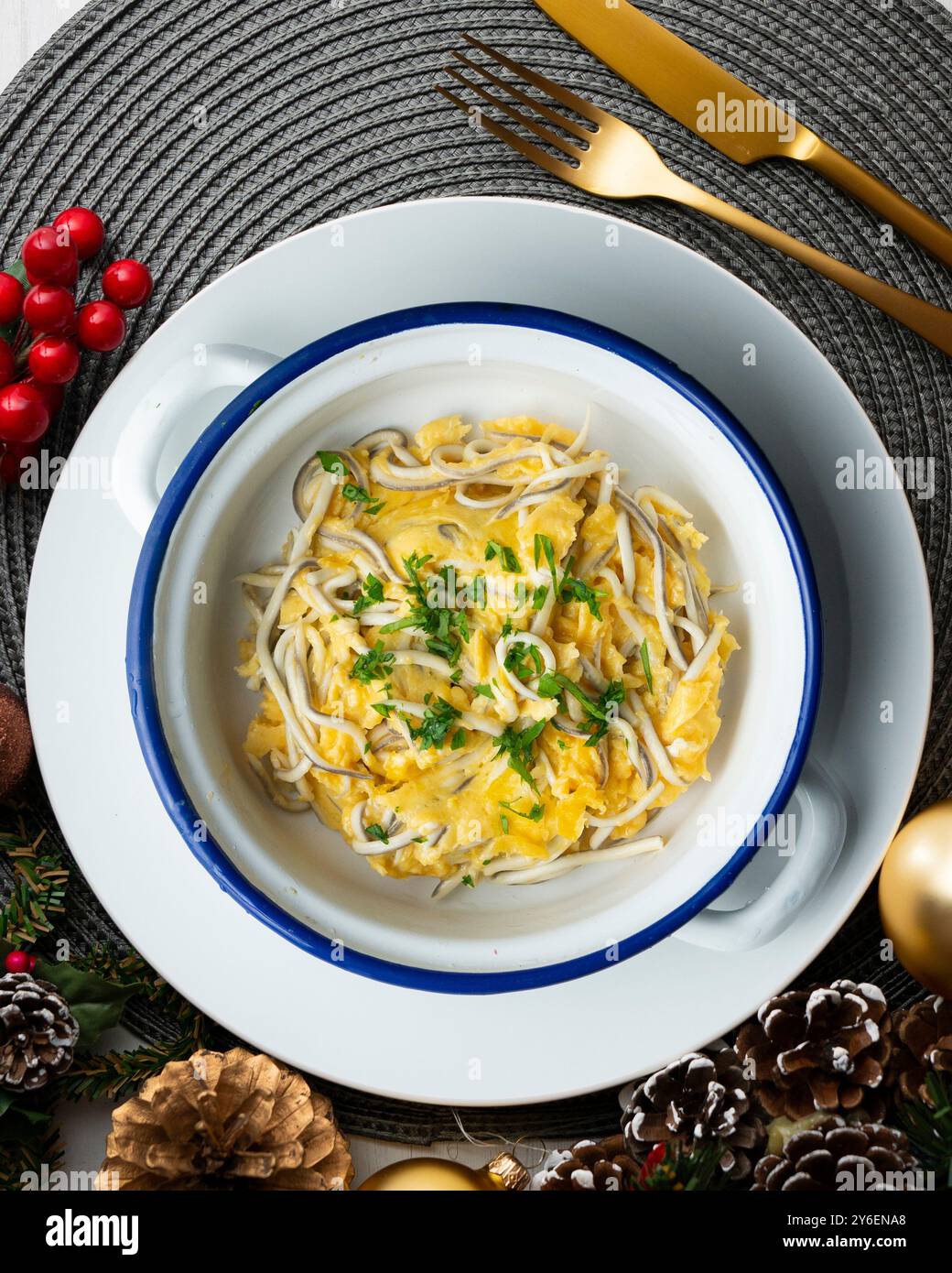 Rührei mit Babyaal und Knoblauch. Tisch mit Blick von oben mit Weihnachtsdekoration. Stockfoto