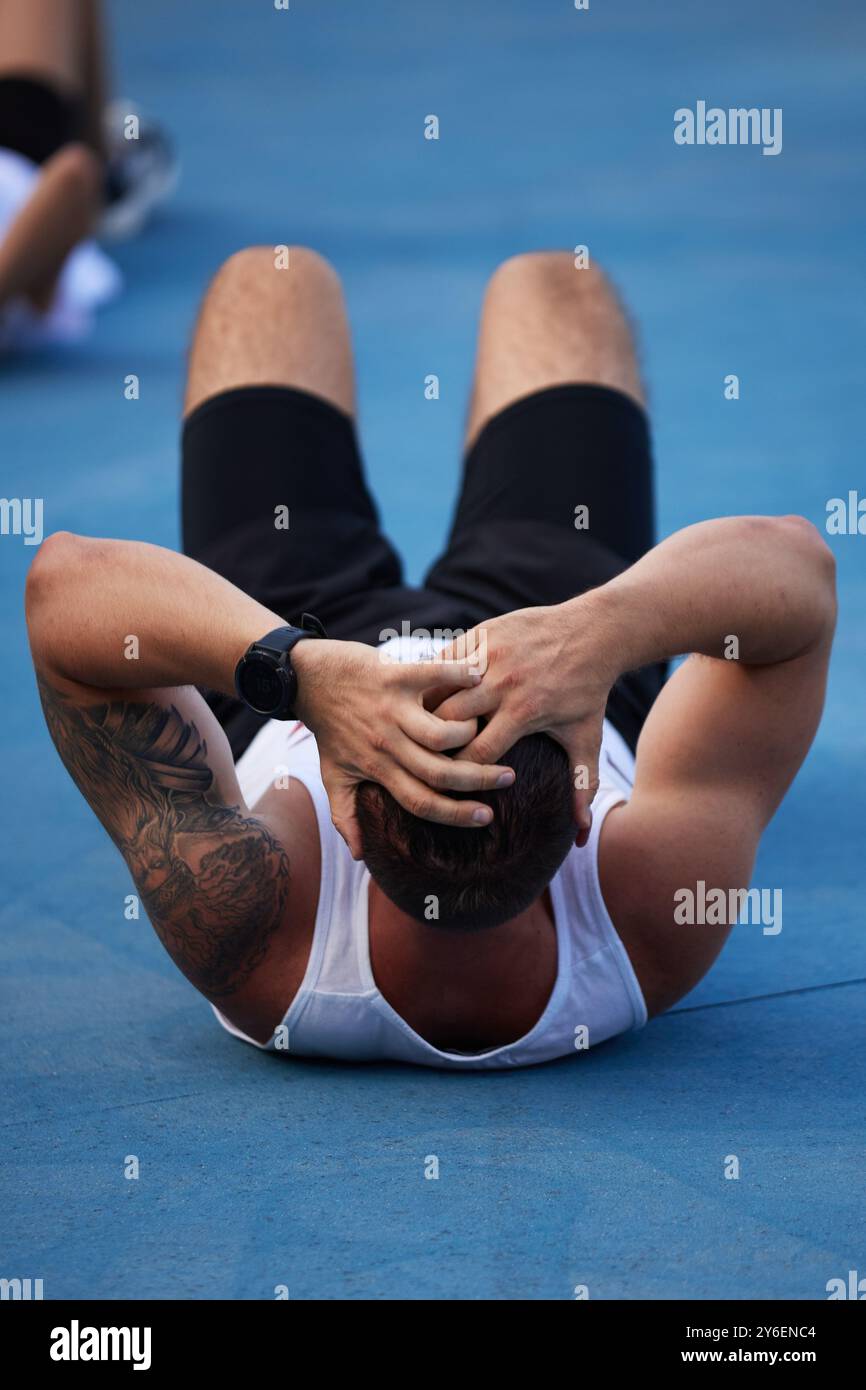 Muskulöser ukrainischer Mann trainiert abs während des Gruppentrainings im Freien in Kiew - 15. September 2024 Stockfoto