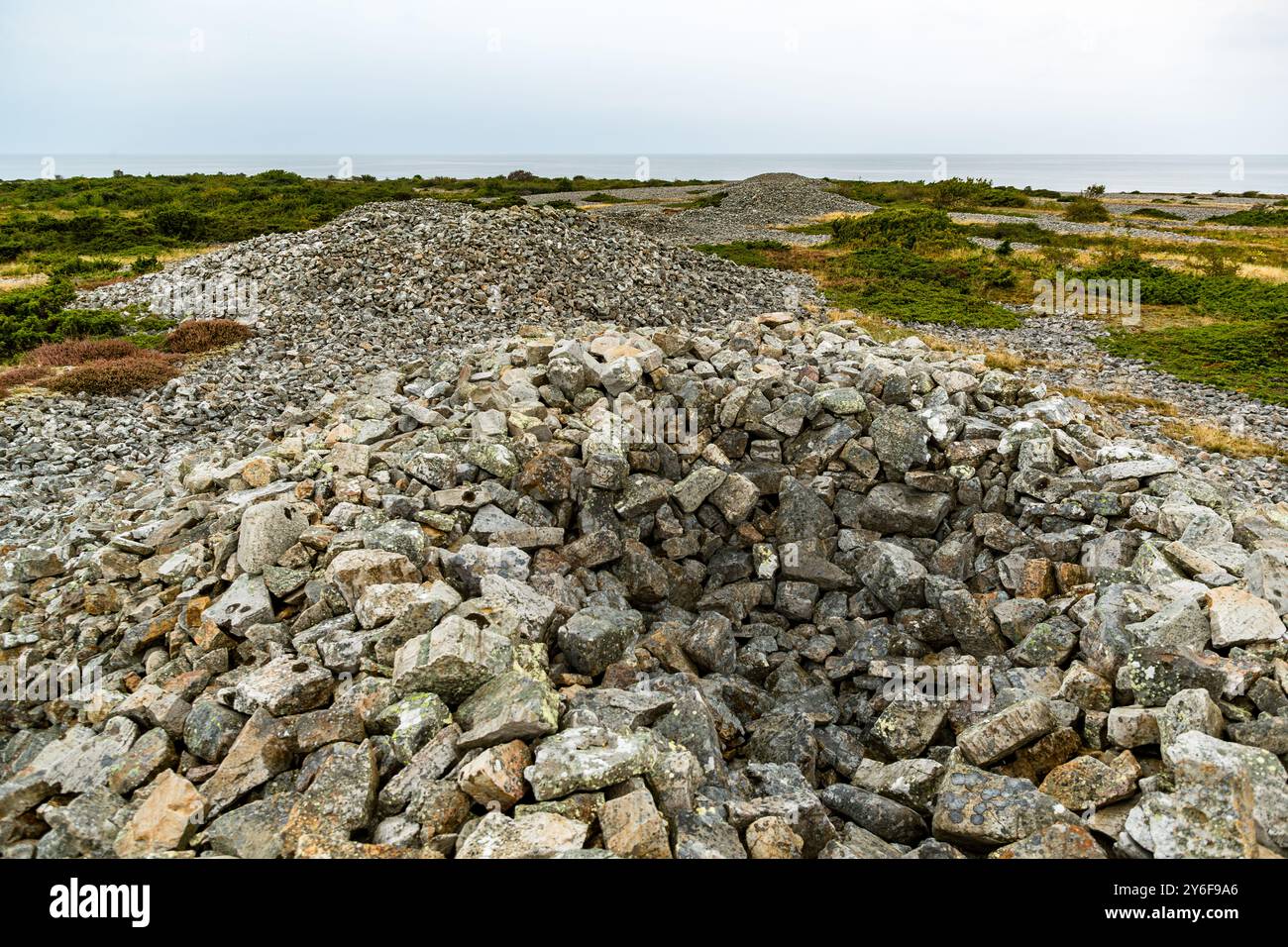 Grobschlächtig behauene, rötlich-braune Feldsteine bilden die Flanke eines der acht Gröthögarna-Grabhügel im Naturreservat Bjärekusten. Plantahagen, Båstads kommun, Skåne, Schweden. Stockfoto