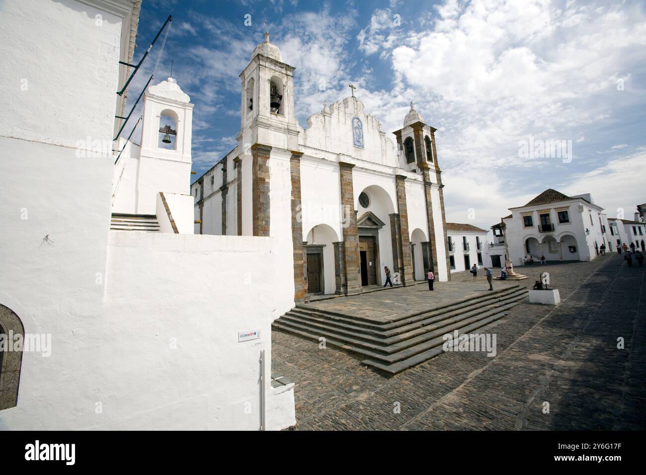 Die befestigte Kirche von Monsaraz steht im Dorf, umgeben von historischer Architektur vor einem blauen Himmel. Stockfoto
