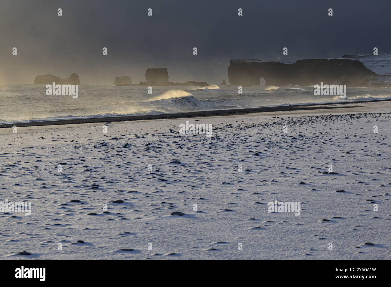 Schneebedeckter Strand, Wellen, Wind, dunkle Wolken, Winter, leichte Stimmung, Felsen, Dyrholaey, Vik, Island, Europa Stockfoto