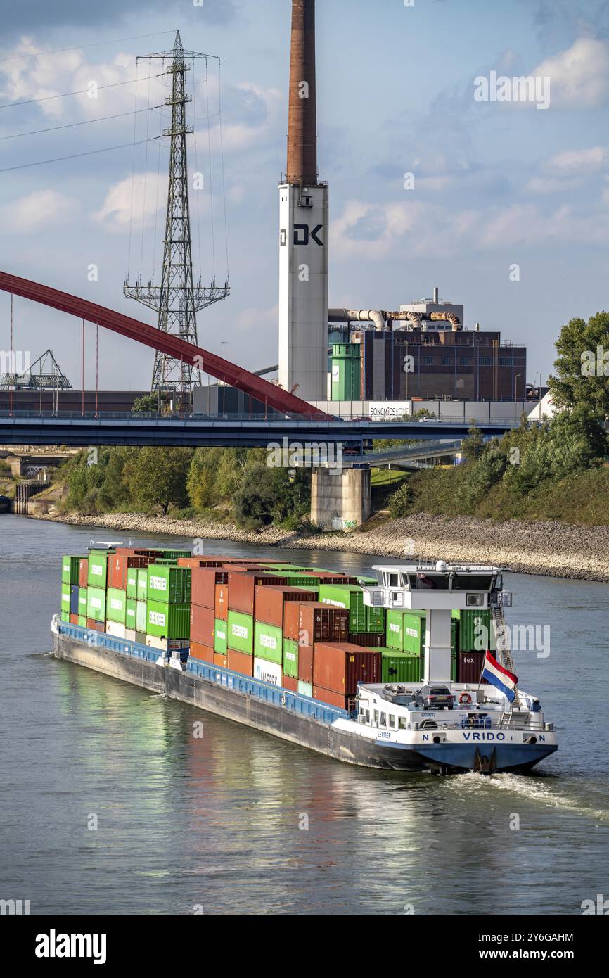 Das mit Containern beladene holländische Frachtschiff Vrido auf dem Rhein bei Duisburg, das hinter der sogenannten Solidaritätsbrücke über den Rhein hinabfährt; Stockfoto