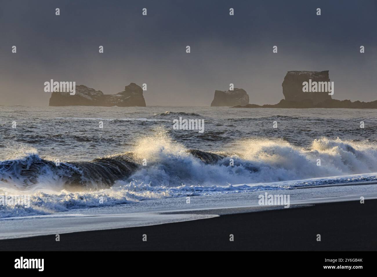 Schneebedeckter Strand, Wellen, Wind, dunkle Wolken, Winter, leichte Stimmung, Felsen, Dyrholaey, Vik, Island, Europa Stockfoto