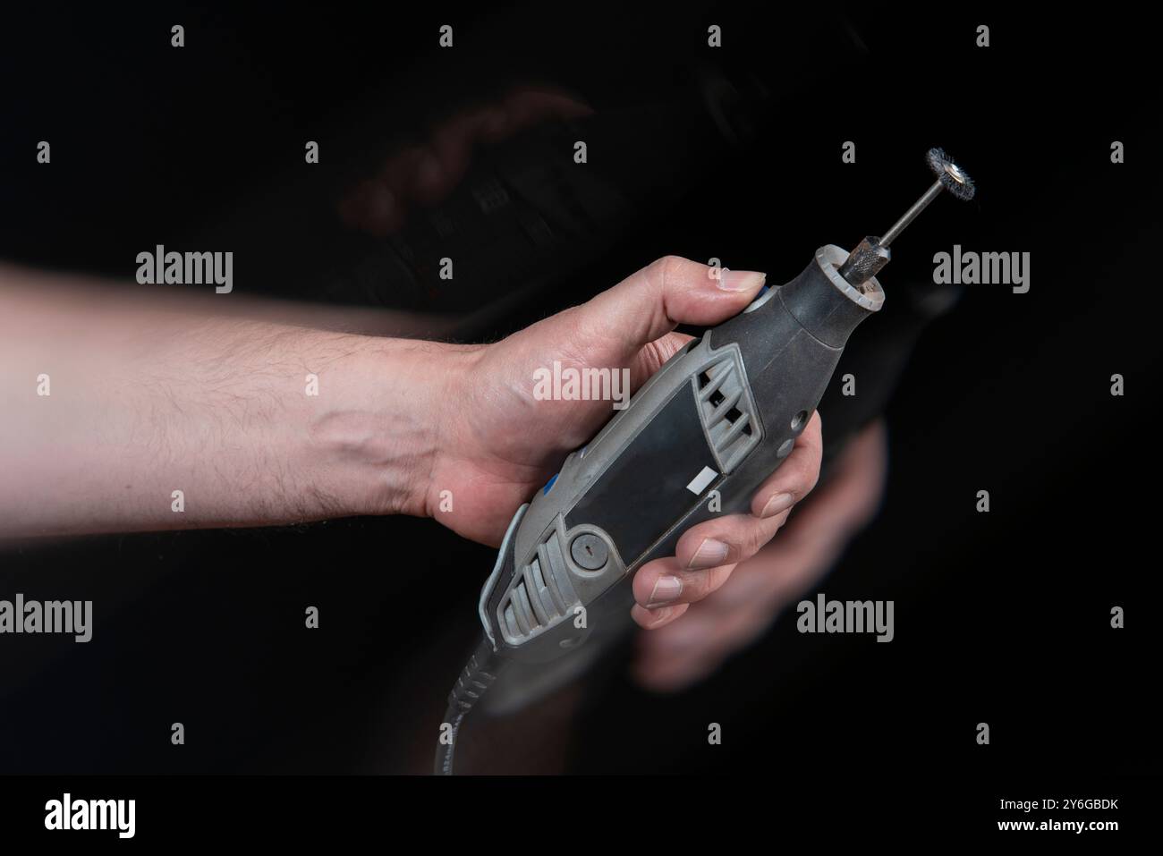Nahaufnahme der Hand eines Mannes, der ein Tischler-Motowerkzeug mit Bewegungseffekt vor schwarzem Hintergrund hält Stockfoto