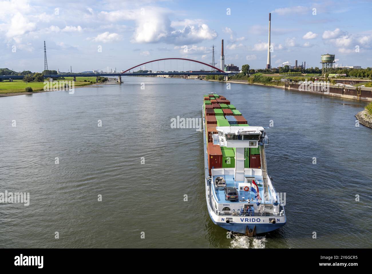 Das mit Containern beladene holländische Frachtschiff Vrido auf dem Rhein bei Duisburg, das hinter der sogenannten Solidaritätsbrücke über den Rhein hinabfährt; Stockfoto