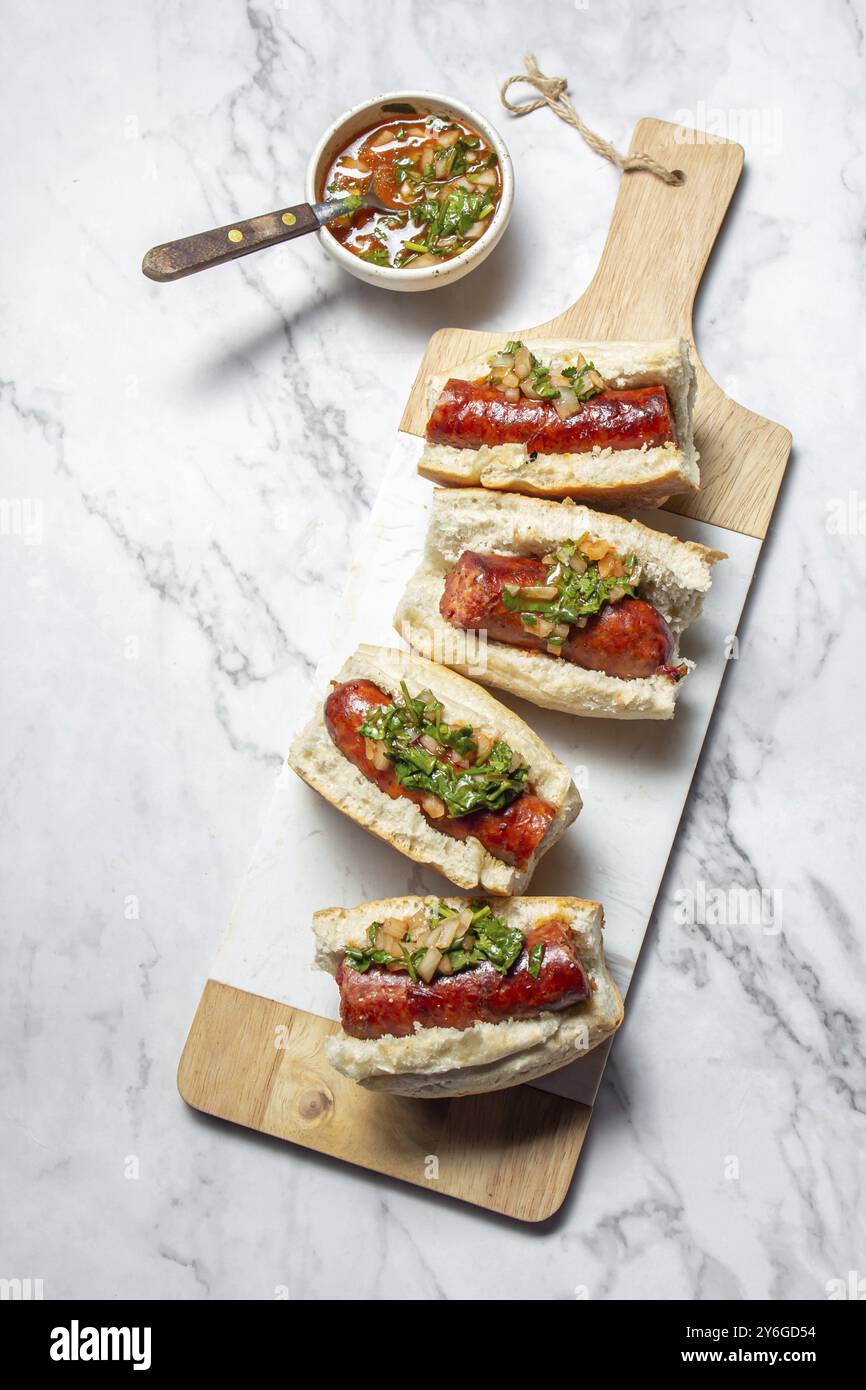 Essen, chilenische und argentinische Küche. Traditionelles Choripan mit würzigem Pebre, Chorizo-Sandwich mit Chorizo-Würstchen und Brot Stockfoto