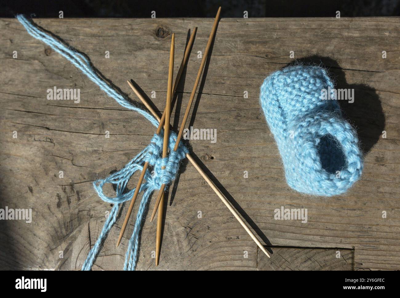 Stricken von Socken aus blauer Wolle, Stricken von Nadeln auf einem Holztisch Stockfoto